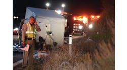 A California Highway Patrol officer stands in front of an overturned trailer after a crash that resulted in eight fatalities.