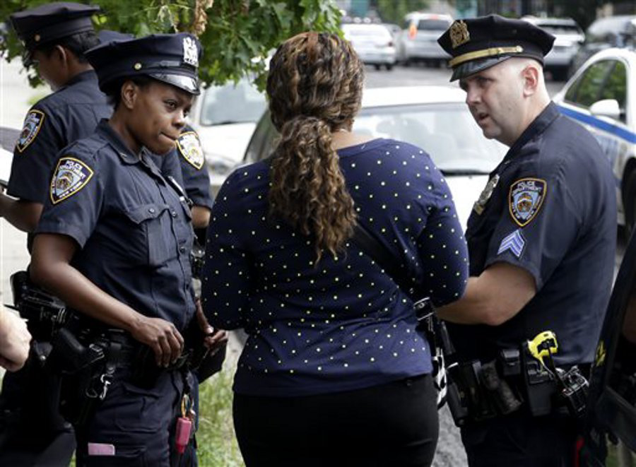 NYPD officers talk with a woman who had her phone stolen in the Brownsville section of Brooklyn on Aug. 13.