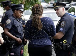 NYPD officers talk with a woman who had her phone stolen in the Brownsville section of Brooklyn on Aug. 13.
