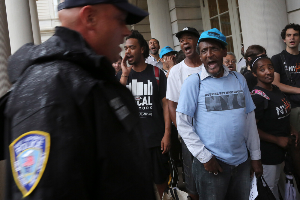 A police officer walks past supporters of the NYPD Oversight override vote on Aug. 22.