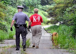 Patti Means, of Red Rose K-9 Search &amp; Rescue, walks with her dog Beemer and a Columbia Borough Police officer along PPL access road in Columbia, Pa. on Aug. 8.