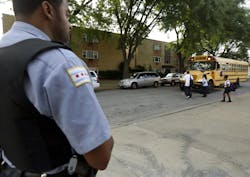 A Chicago Police officer patrolling the neighborhood watches school children board a buss outside Gresham Elementary School on the first day of classes on Aug. 26. A Chicago Police officer patrolling the neighborhood watches school children board a buss outside Gresham Elementary School on the first day of classes on Aug. 26.