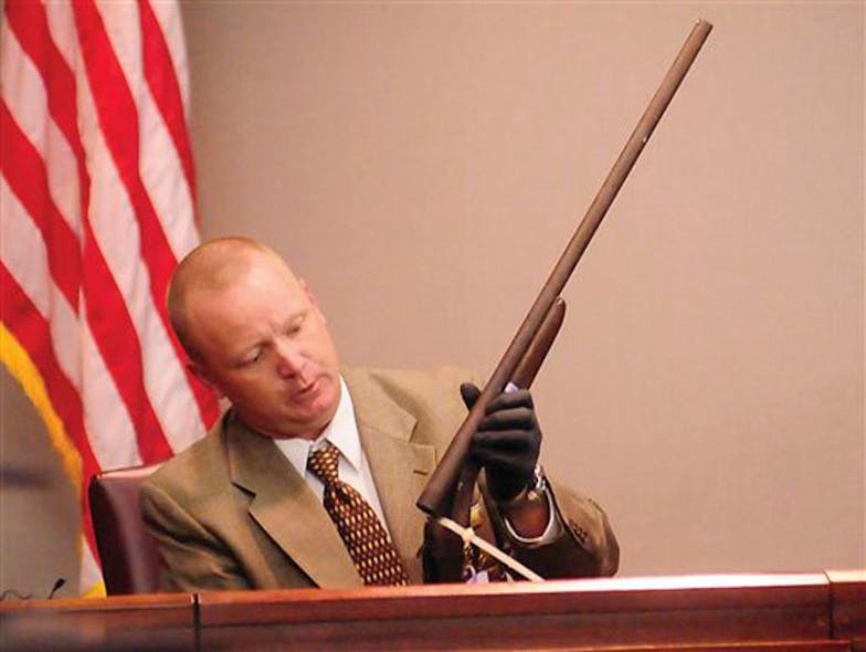Glynn County Police Lt. Keith Stalvey shows the jury a shotgun taken from the trunk of the car Guy Heinze Jr. was driving when he returned home Aug. 29, 2009 to find his father and seven others dead in the trailer where lived with them, during Heinze&apos;s trial on Oct. 16.