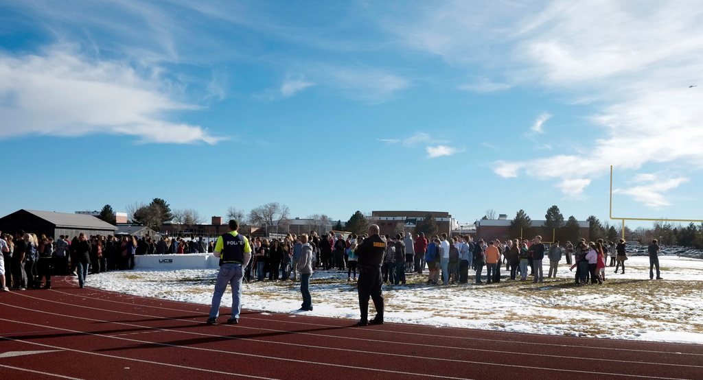 Sheriffs deputies stand guard over students after they were evacuated to the track and football field at Arapahoe High School in Centennial, Colo. on Dec. 13.