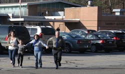 A police officer leads two women and a child from Sandy Hook Elementary School in Newtown, Conn., where a gunman opened fire, killing 26 people, including 20 children on Dec. 14, 2012.