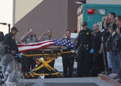 Law enforcement officers salute as the body of a Bay Area Rapid Transit police officer draped with the American flag is loaded into an Alameda County Sheriff&apos;s Coroner vehicle.
