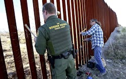 A Border Patrol agent, left, joins Glenn Weyant for a duet, as they bang mallets against the border fence in Sasabe, Ariz., turning it into a musical instrument on Jan. 25.