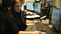 Cathy Eckhardt is seen working, with Paul Munson in the background, inside the New York State Police Forensic Video and Multimedia Services unit's newly renovated office.