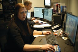 Cathy Eckhardt is seen working, with Paul Munson in the background, inside the New York State Police Forensic Video and Multimedia Services unit's newly renovated office. Cathy Eckhardt is seen working, with Paul Munson in the background, inside the New York State Police Forensic Video and Multimedia Services unit's newly renovated office.