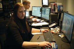 Cathy Eckhardt is seen working, with Paul Munson in the background, inside the New York State Police Forensic Video and Multimedia Services unit&apos;s newly renovated office.