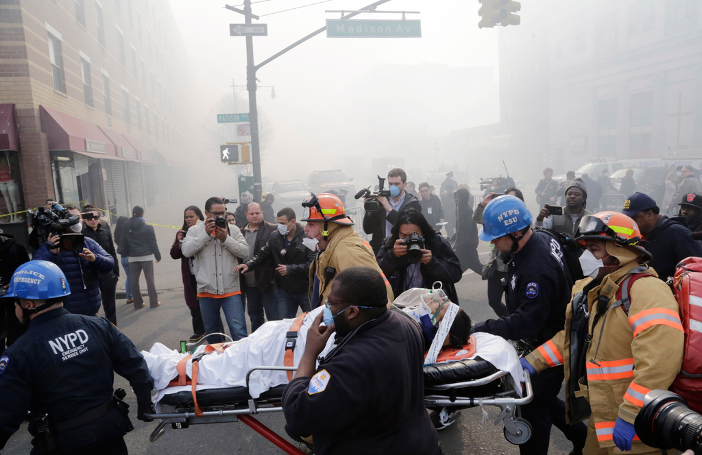 Rescue workers remove an injured person on a stretcher after a possible explosion and building collapse in the East Harlem neighborhood of New York on March 12.