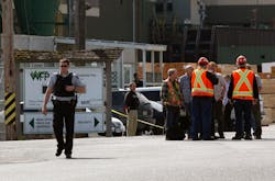 Mill workers talk as a police officer walks away following a shooting at Western Forest Products in Nanaimo, British Columbia on April 30. Mill workers talk as a police officer walks away following a shooting at Western Forest Products in Nanaimo, British Columbia on April 30.