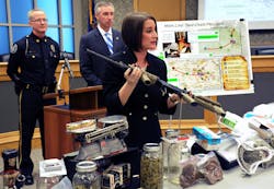 Montgomery County district attorney Risa Vetri Ferman holds a rifle that was part of the drugs, guns, money and other illegal items seized when Lower Merion Police broke up a drug distribution ring in Montgomery County, Pa.