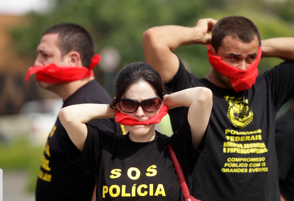 Federal police wearing T-shirts that read in Portuguese 'SOS Federal Police' cover their mouths with bandanas as a way to protest their leaders' recommendation to not protest.
