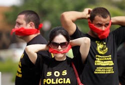 Federal police wearing T-shirts that read in Portuguese 'SOS Federal Police' cover their mouths with bandanas as a way to protest their leaders' recommendation to not protest. Federal police wearing T-shirts that read in Portuguese 'SOS Federal Police' cover their mouths with bandanas as a way to protest their leaders' recommendation to not protest.