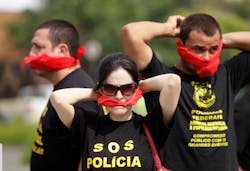 Federal police wearing T-shirts that read in Portuguese &apos;SOS Federal Police&apos; cover their mouths with bandanas as a way to protest their leaders&apos; recommendation to not protest.