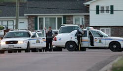 Royal Canadian Mounted Police officers take cover behind their vehicles in Moncton, New Brunswick, on June 4.