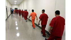 Detainees walks along a hallway of the largest immigrant detention facility in Southern California.