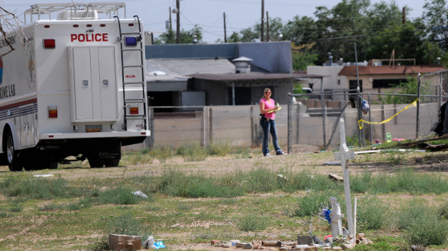 Albuquerque police work at the scene where two men were found dead in a open area just north of Central Avenue at 60th Street on July 19.
