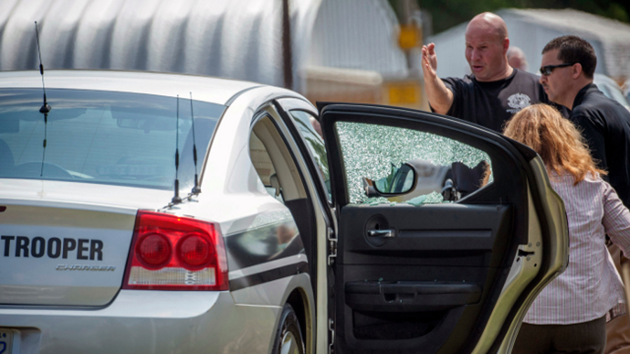 Law enforcement officers look over a highway patrol vehicle that had its window shot out in Fayetteville, N.C. on July 30.