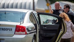 Law enforcement officers look over a highway patrol vehicle that had its window shot out in Fayetteville, N.C. on July 30.