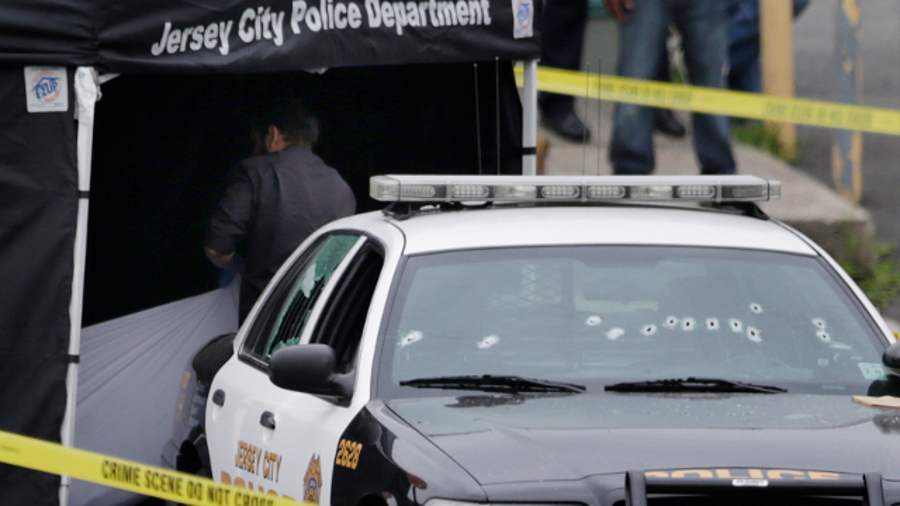 Investigators pull a sheet over the body of a suspect who allegedly shot a Jersey City Police Department officer responding to a call at a 24-hour pharmacy on July 13.