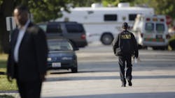 Acting Harvey Police Chief Denard Eaves, right, walks back to a command vehicle as law enforcement officials continue to negotiate with at least one hostage-taker for the release of two children and two adults he is still holding inside a house in the southern Chicago suburb of Harvey on Aug. 20.