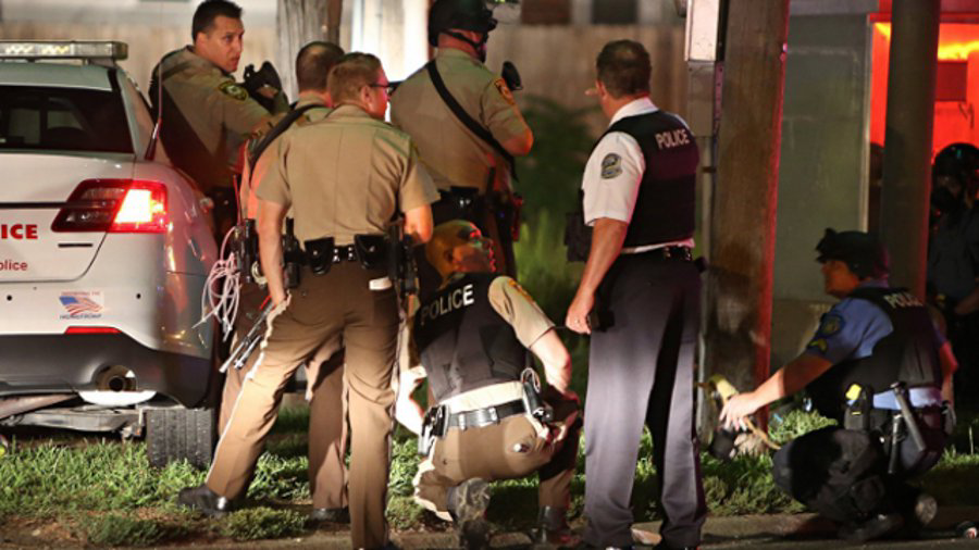 Police take cover near a QuikTrip in 9400 block of W. Florissant Avenue after shots were fired at them in Ferguson, Mo. on Aug. 11, 2014.