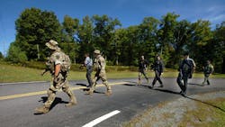 Members of the Pennsylvania State Police and law enforcement conservation officers walk from the state police barracks to a wooded area across the street on Route 402.