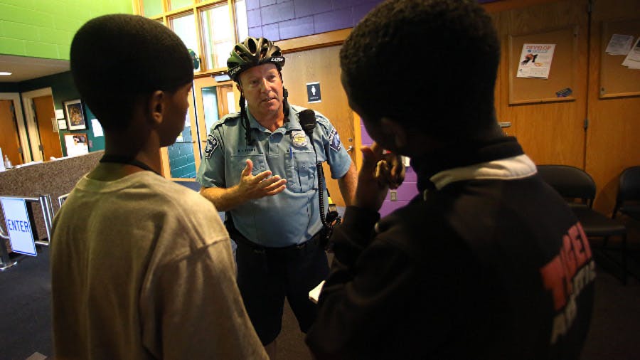 Minneapolis Police Officer Mike Kirchen talks with Mohamed Salat, left, and Abdi Ali at a community center where members of the Somali community gather.