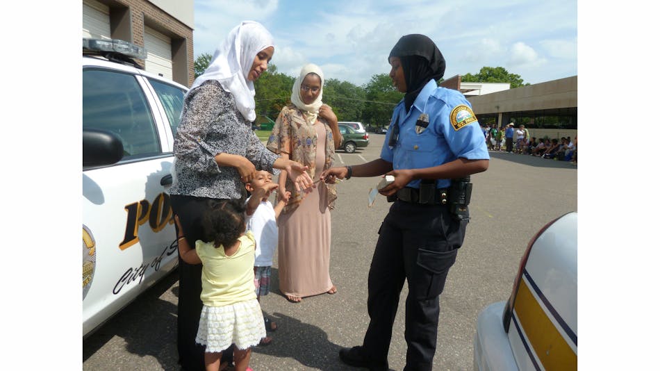 Kadra Mohamed hands out police badge stickers at a community event attended by Somali families.