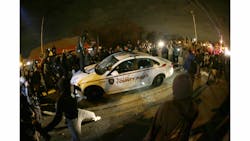 A protester squirts lighter fluid on a police car as the car windows are shuttered near the Ferguson Police Department on Nov. 24. A protester squirts lighter fluid on a police car as the car windows are shuttered near the Ferguson Police Department on Nov. 24.