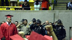 As Dakota, the son of Deputy Sonny Smith, walks across the stage, a group of officers salutes him. As Dakota, the son of Deputy Sonny Smith, walks across the stage, a group of officers salutes him.