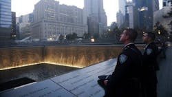 Two Port Authority police officers look on at a reflecting pool at the National September 11 Memorial & Museum in New York City. Two Port Authority police officers look on at a reflecting pool at the National September 11 Memorial & Museum in New York City.