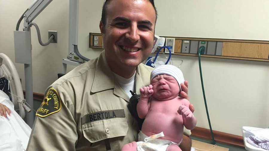Los Angeles County Sheriff's Deputy Roger Bertola hold the baby girl he helped deliver in the parking lot of a car wash Wednesday morning.