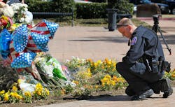 A DFW Airport police officer kneels at the growing memorial at the Euless Police Headquarters on March 2 in Euliss, Texas.