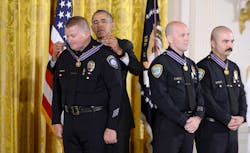 President Barack Obama awards Santa Monica Police Department Officers Jason Salas (R) and Robert Sparks and Captain Raymond Bottenfield (L) with the 2013-2014 Public Safety Office Medal of Valor during a ceremony in the East Room of the White House on May 16 in Washington, D.C.