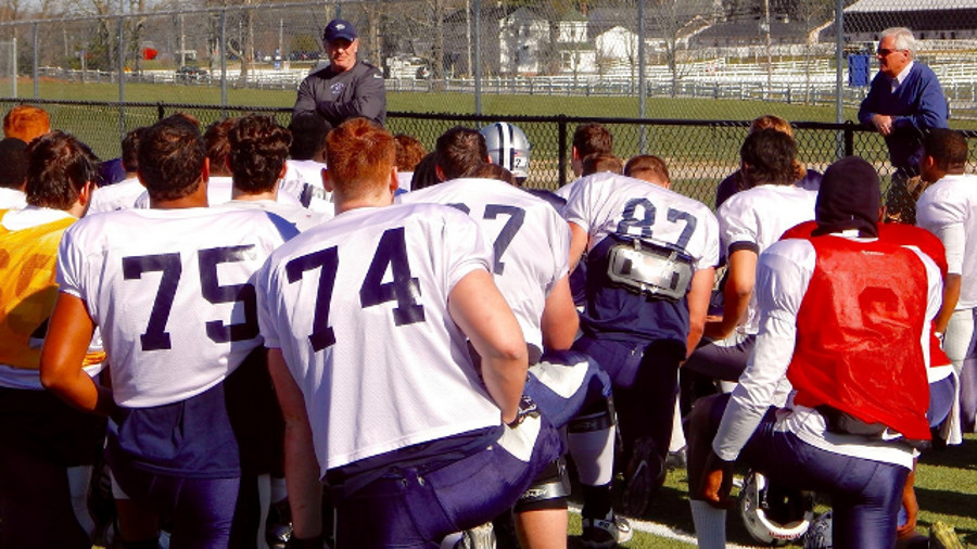University of New Hampshire President Mark Huddleston, right, stopped by football practice on April 21 to commend four Wildcats who recently came to the aid of a state trooper being attacked by a suspected drunk driver.