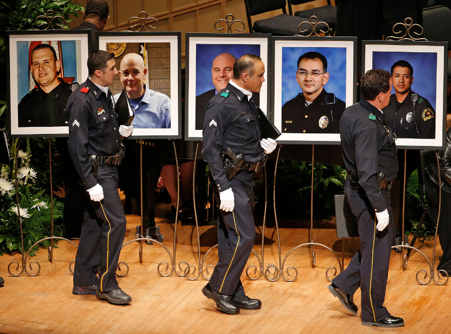 Members of the Dallas Police Department Choir walk past portraits of their fallen comrades during a memorial for five Dallas and DART police officers shot to death in last week's attack on July 12 at the Morton H. Meyerson Symphony Center in Dallas.