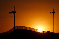 Sunset at the U.S.-Mexico border in Naco, Ariz., where a Border Patrol agent in his car keeps an eye on activity.