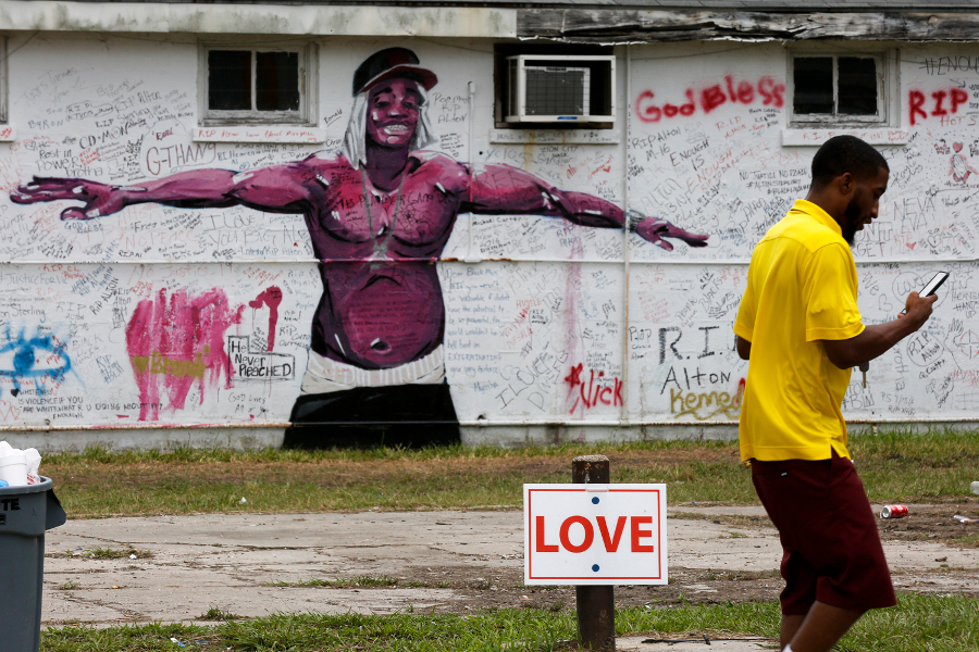 A pedestrian walks past a mural and a memorial wall for Alton Sterling in Baton Rouge, La., on July 18, 2016. The Department of Justice, declining comment, will not bring federal civil rights charges against two police officers involved in Sterling's death.