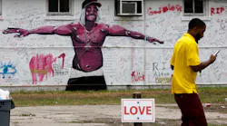 A pedestrian walks past a mural and a memorial wall for Alton Sterling in Baton Rouge, La., on July 18, 2016. The Department of Justice, declining comment, will not bring federal civil rights charges against two police officers involved in Sterling's death.