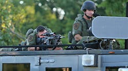 A police sharpshooter keeps an eye on protesters along W. Florissant Avenue on Tuesday, Aug. 12, 2014, in Ferguson, Mo.