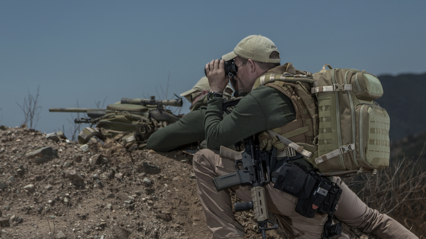 A sniper, using the Riftblade as his rifle rest, and his spotter, wearing a matching backpack, prepare to take a shot.