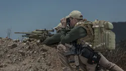 A sniper, using the Riftblade as his rifle rest, and his spotter, wearing a matching backpack, prepare to take a shot.