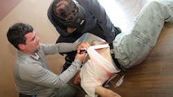 Gaining clear access to wounds for treatment is a priority. Students practice this on a role player. Seen here and in following photos, our Editorial Director Lt. Frank Borelli participates as the role player. Gaining clear access to wounds for treatment is a priority. Students practice this on a role player. Seen here and in following photos, our Editorial Director Lt. Frank Borelli participates as the role player.
