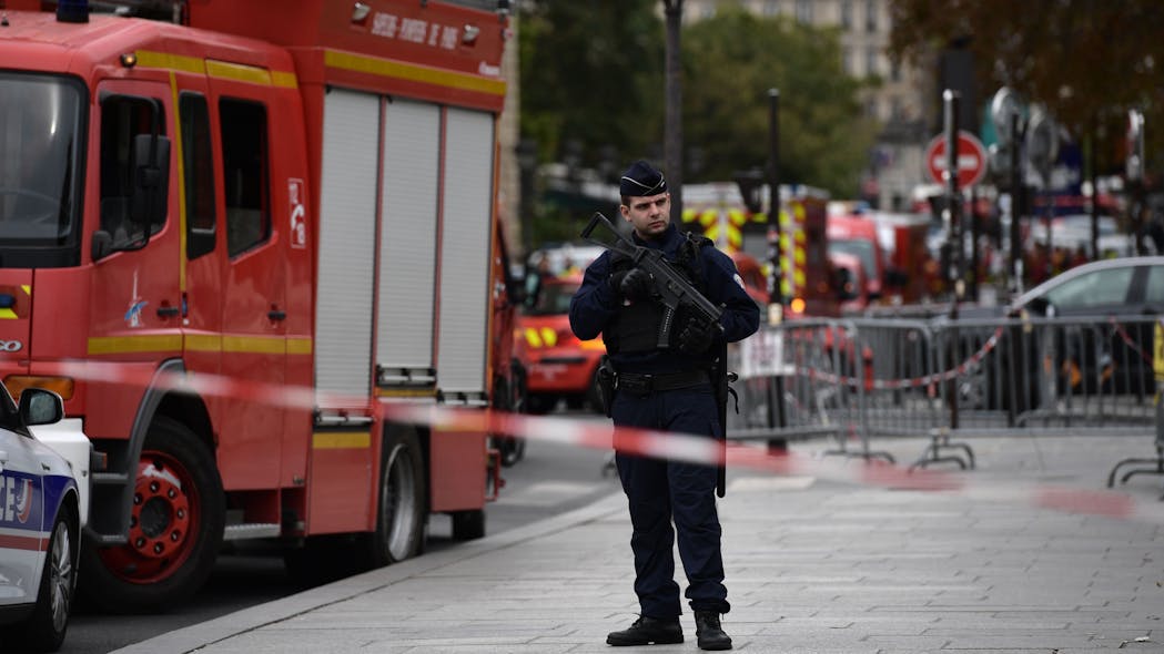 A policeman stands next to firefighter vehicles near Paris police headquarters on Oct. 3, 2019 after four officers were killed in a knife attack. The attacker was shot dead after killing four officers at police headquarters in the historical centre of Paris.