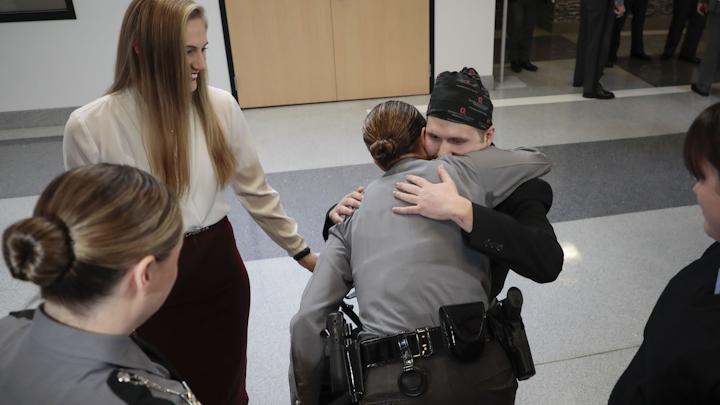 State Highway Patrol Trooper Jason Phillips, center, gets a hug from Sgt. Kristi Comstock before a recognition ceremony on Wednesday at the Ohio State Highway Patrol Training Academy in Columbus. His sister, Crystal Short, is upper left. Sgt. Comstock was among the first responders to the scene of an accident where Phillips, 23, collided head-on with a wrong-way impaired driver in June 2019. A number of motorists stopped to help Trooper Phillips out of his vehicle immediately following the wreck. The Highway Patrol recognized these civilians along with other first responders and medical personnel who helped save Trooper Phillips's life.
