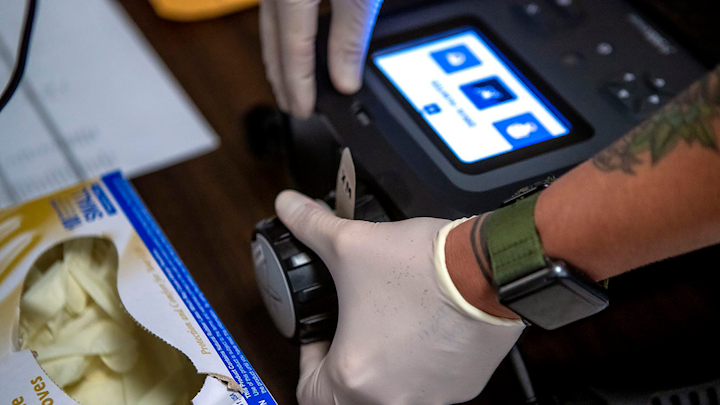 Sarak Mackin inserts the test swab with the trace sample into the MX908.
