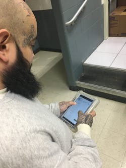 Jesus Villegas, an incarcerated individual at the Kendall County Sheriff&apos;s Office in Illinois, uses the photo attachment featured of the eMessaging application on SecurueView Tablets from Securus Technologies to view pictures of photos of family and friends.